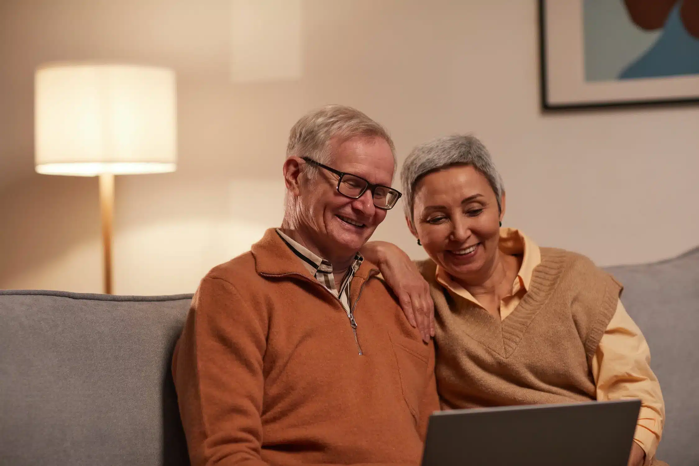 A happy older couple in Cary, NC, looking at their dental implants photos on a laptop